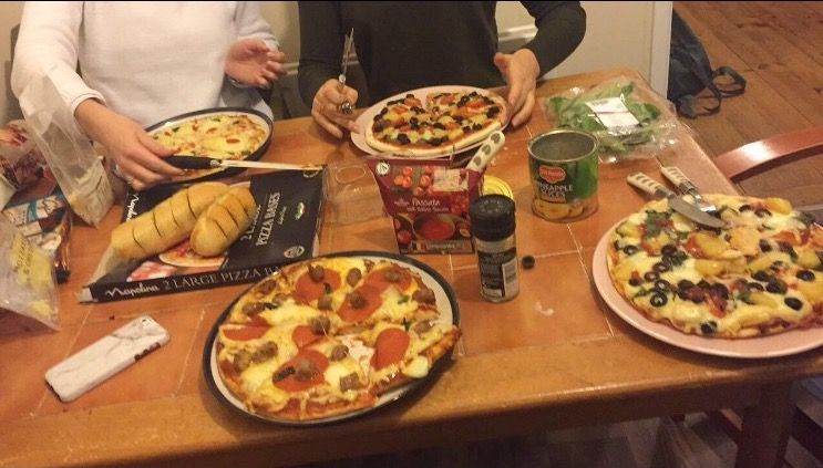 Image may contain: Furniture, Dining Table, Table, Human, Person, Food, Pizza