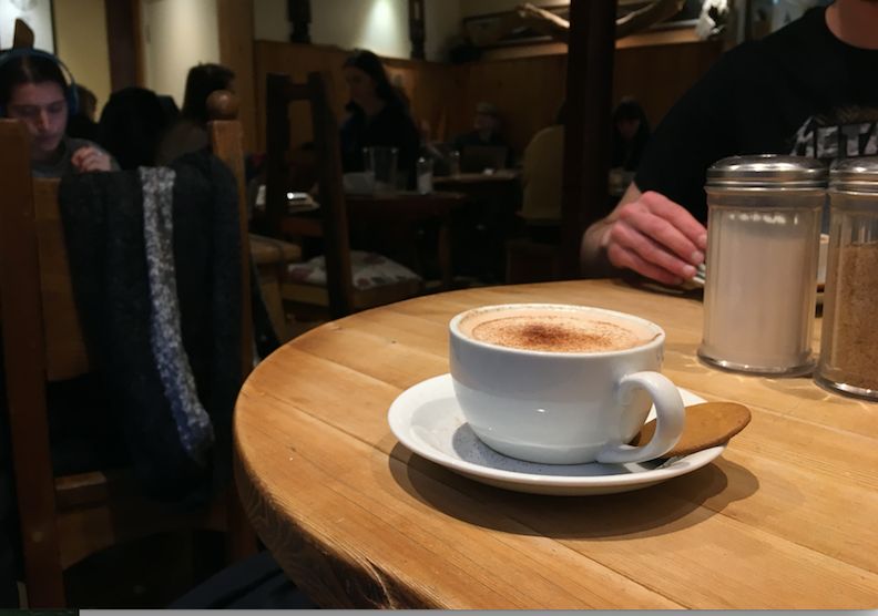 Image may contain: Dining Table, Furniture, Table, Cafe, Restaurant, Beverage, Drink, Latte, Coffee Cup, Cup, Pottery, Saucer, Person, Human