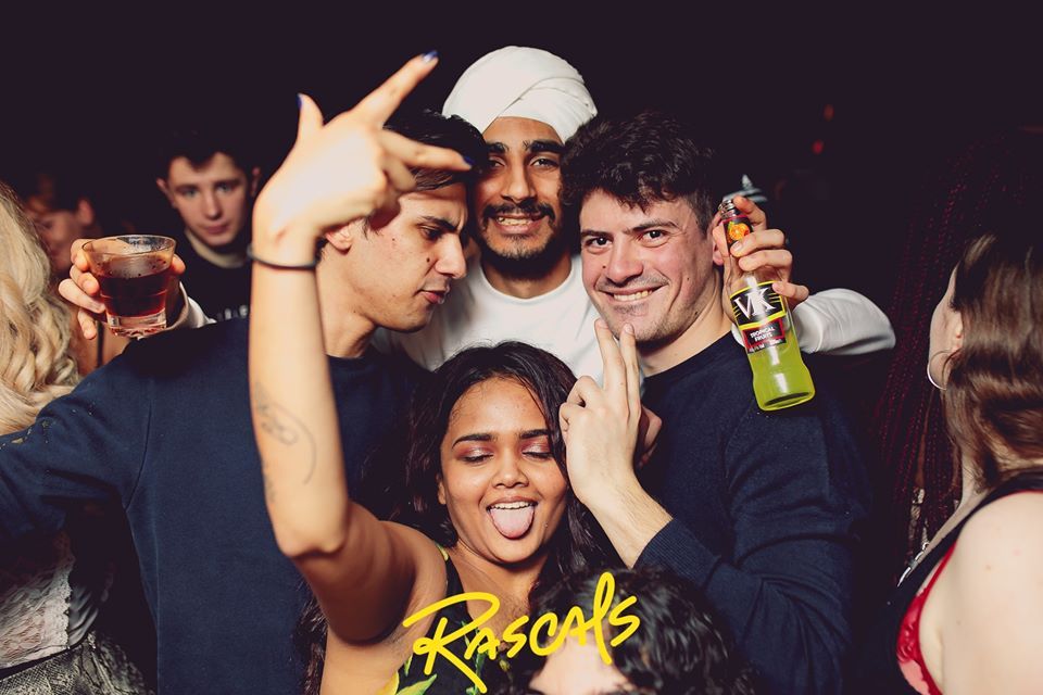 Image may contain: Night Club, Apparel, Hat, Clothing, Beer, Bottle, Alcohol, Club, Beverage, Drink, Face, Party, Human, Person