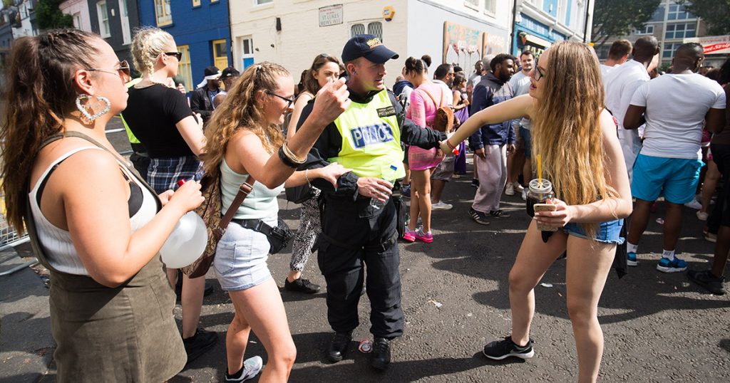 Girls dance with a police officer at Notting Hill Carnival, London. 29 August 2016.