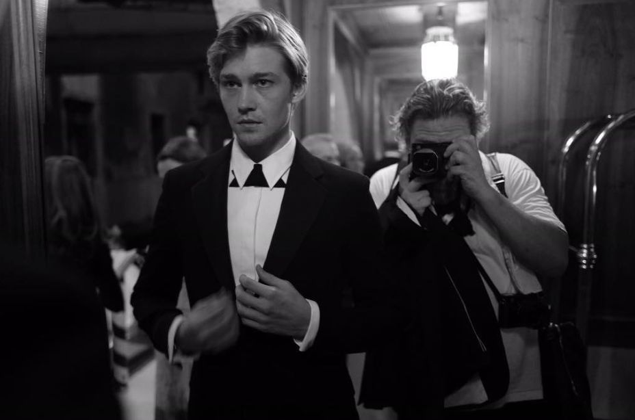 Image may contain: who is Joe Alwyn, Joe Alwyn, Taylor Swift boyfriend, engagement, Taylor Swift, Photo, Photography, Tuxedo, Camera, Electronics, Photographer, Accessory, Accessories, Tie, Apparel, Coat, Suit, Clothing, Overcoat, Human, Person
