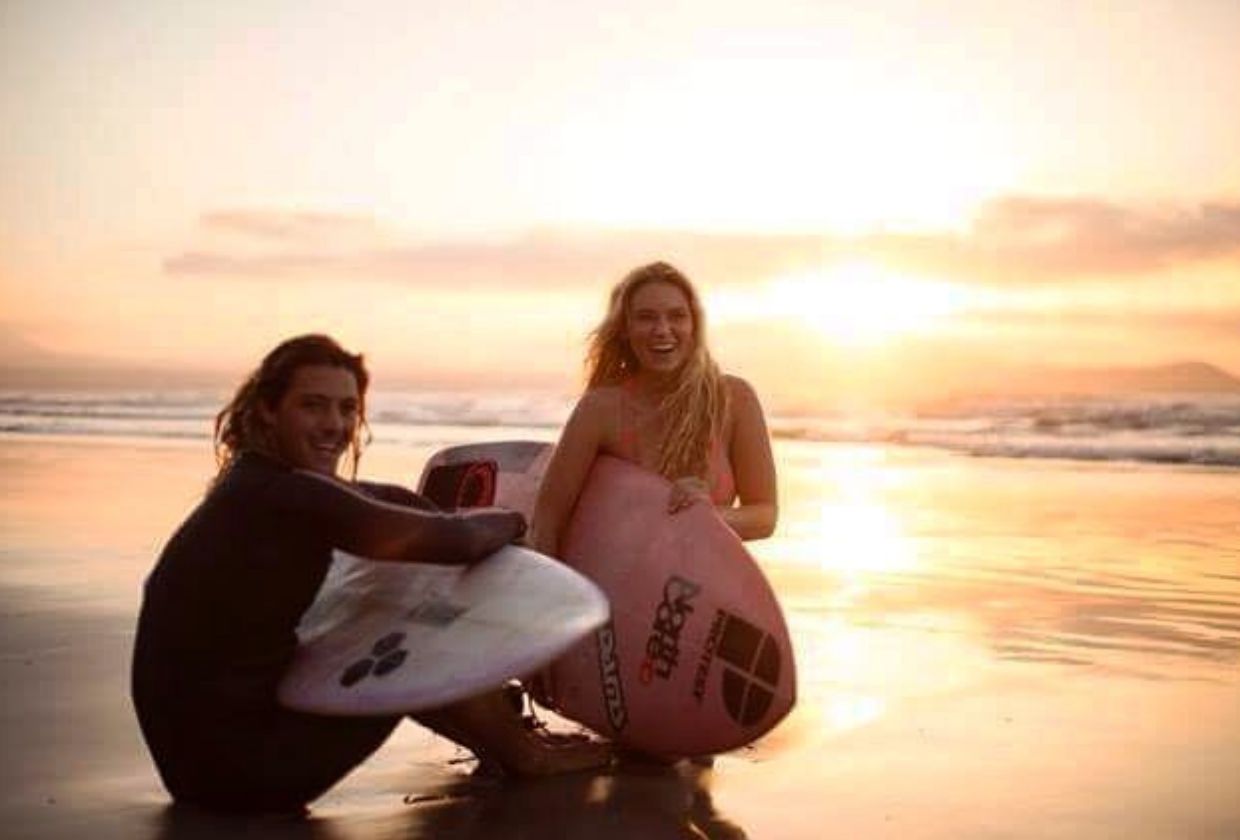 Image may contain: Female, Surfboard, Sky, Sunrise, Face, Vacation, Coast, Beach, Surfing, Sea Waves, Sport, Sports, Shoreline, Person, Human, Nature, Water, Outdoors, Sea, Ocean