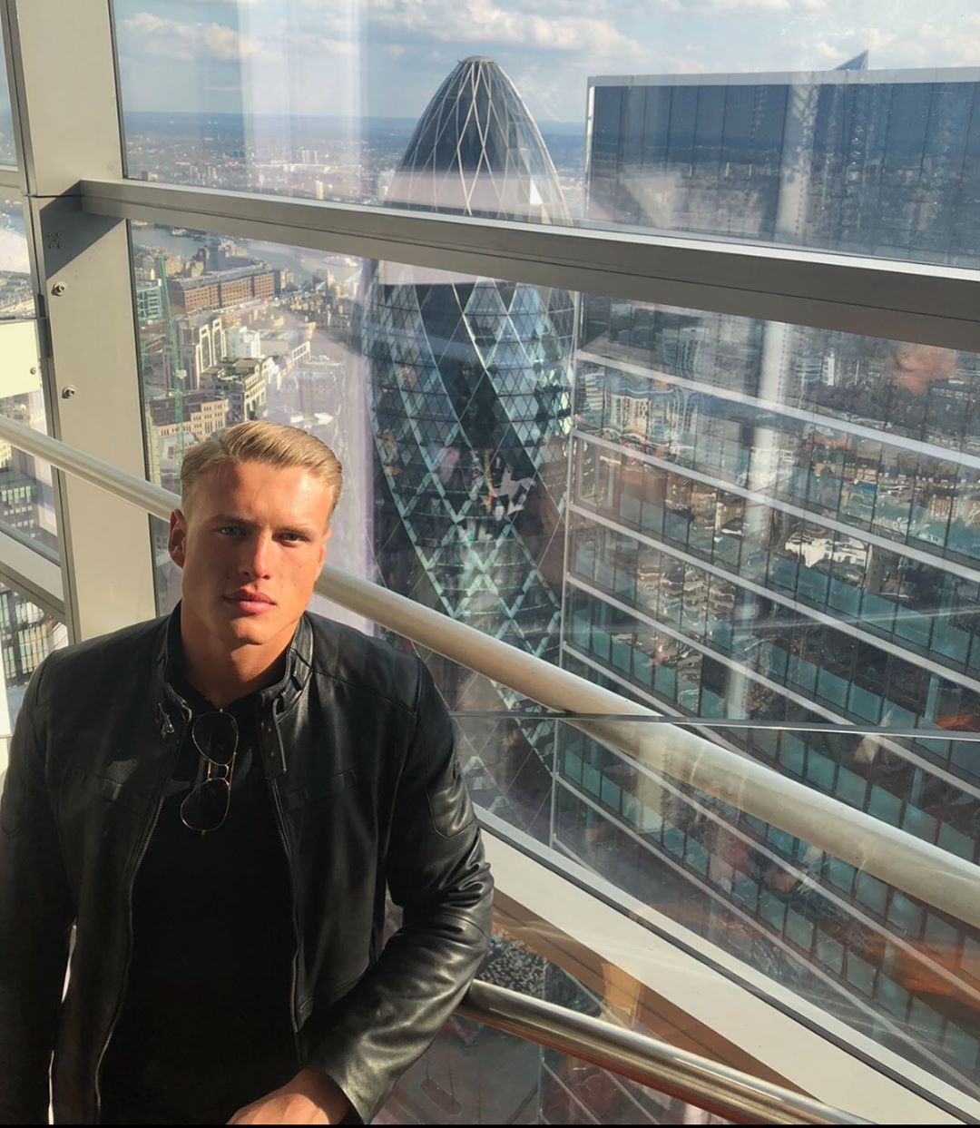Image may contain: Casa Amor cast, Casa Amor, Love Island, George Rains, contestant, cast, Islander, new, boy, Instagram, age, job, Leather Jacket, Town, Urban, Metropolis, City, Building, Banister, Handrail, Human, Person, Jacket, Coat, Clothing, Apparel