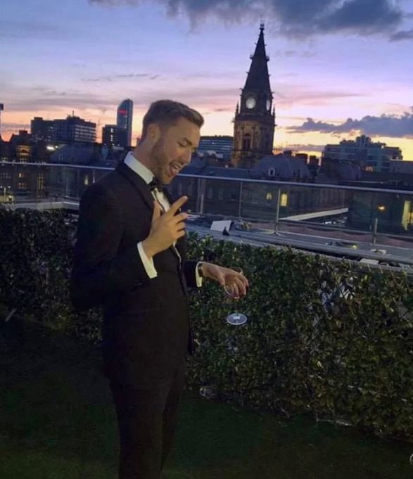Image may contain: Outdoors, Clock Tower, Man, Tuxedo, Blazer, Jacket, Downtown, High Rise, Architecture, Tower, Spire, Steeple, Human, Person, Urban, City, Town, Metropolis, Building, Suit, Coat, Overcoat, Apparel, Clothing