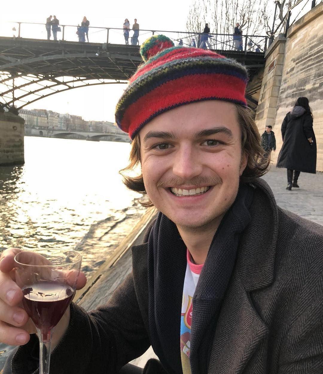 Image may contain:  Stranger Things cast ages, Stranger Things, 3, cast, age, old, birthday, Joe Keery, Steve, Beer Glass, Glass, Beverage, Drink, Alcohol, Beer, Coat, Clothing, Apparel, Person, Human