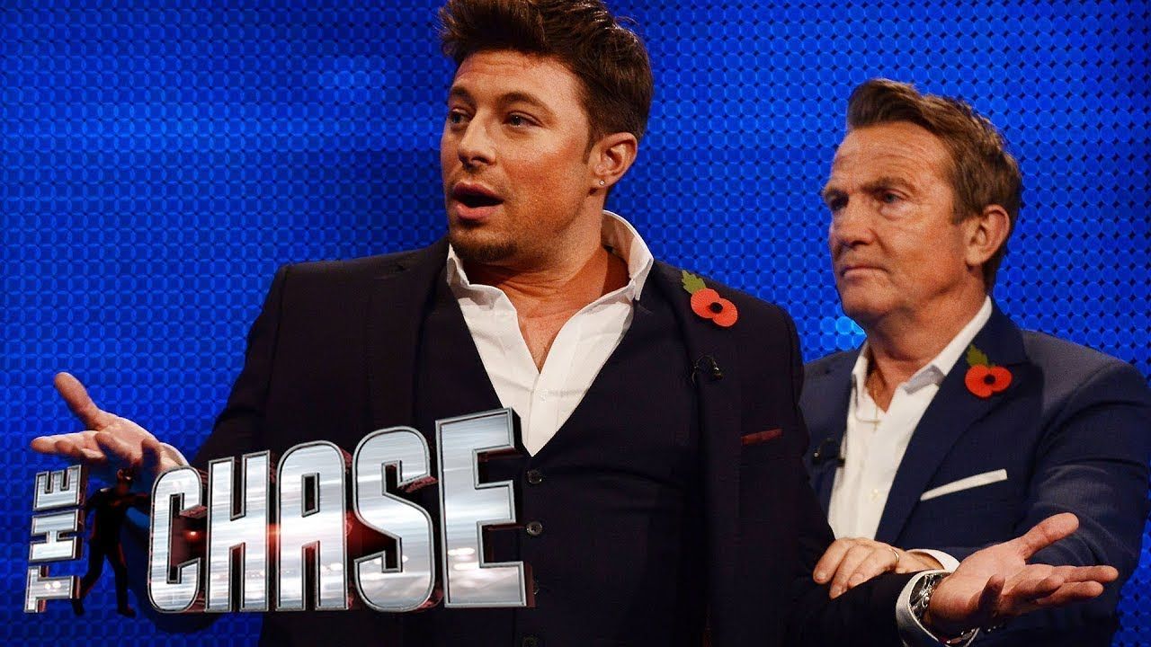 Image may contain: The Chase biggest wins, The Chase, ITV, Celebrity chase, Duncan James, Bradley Walsh, prize, fund, winners, money, cash, final, builder, chaser, Home Decor, Audience, Overcoat, Coat, Suit, Clothing, Apparel, Crowd, Human, Person
