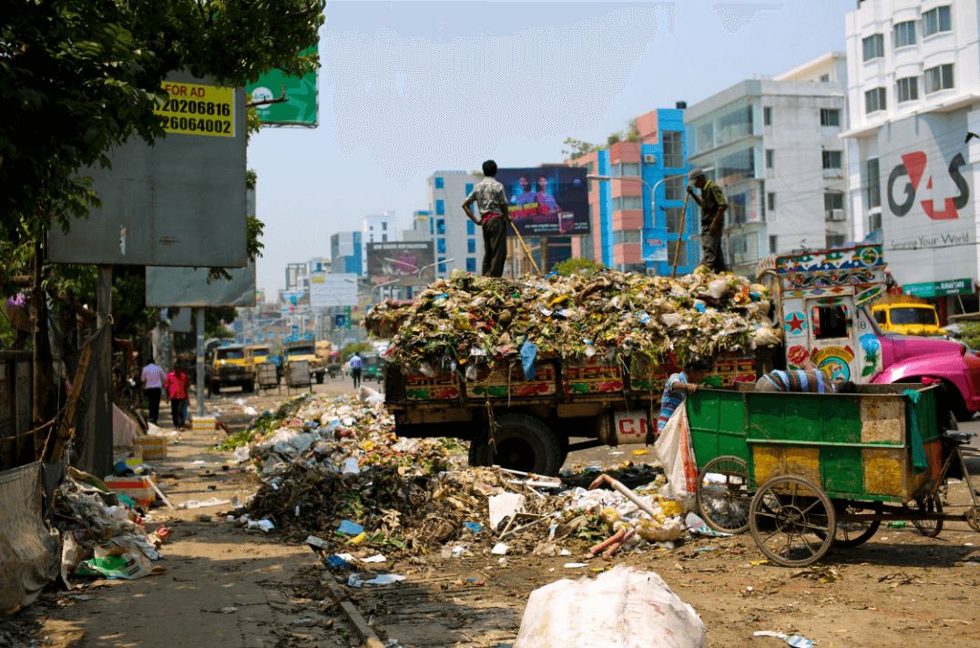 Image may contain: Metropolis, Town, City, Building, Vehicle, Truck, Transportation, Urban, Wheel, Machine, Trash, Person, Human