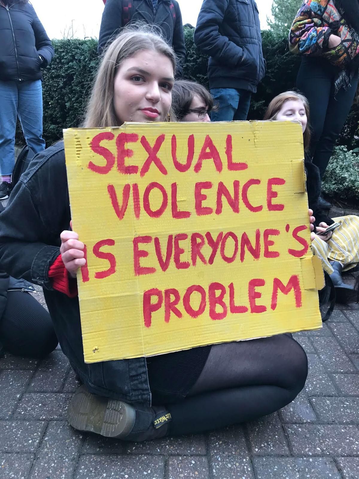 Image may contain: Plant, Crowd, Clothing, Pants, Apparel, Banner, Text, Person, Human, Word