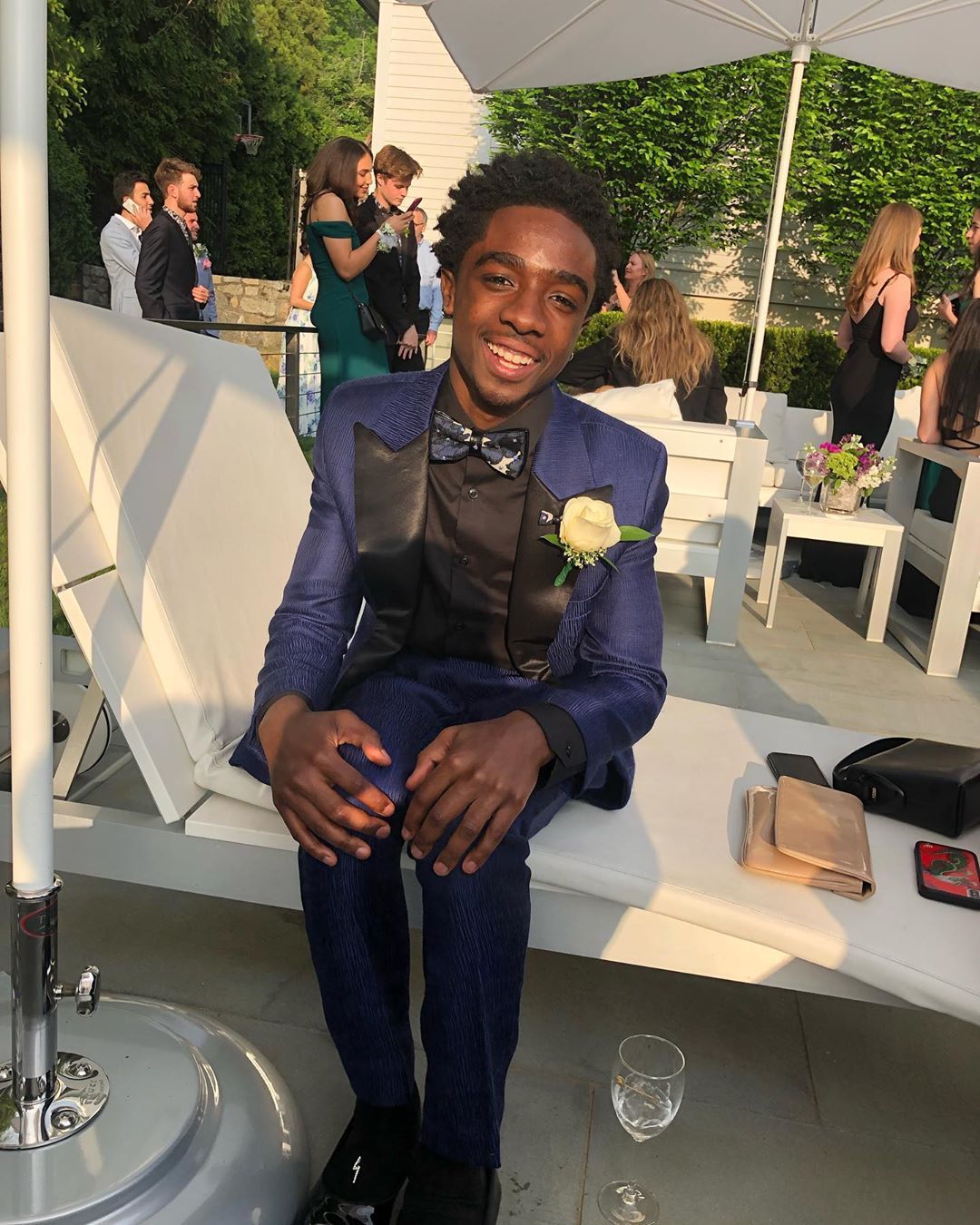 Image may contain:  Stranger Things cast ages, Stranger Things, 3, cast, age, old, birthday, Caleb McLaughlin, Lucas, Table, Overcoat, Coat, Suit, Chair, Furniture, Shoe, Footwear, Pants, Sitting, Person, Human, Apparel, Clothing
