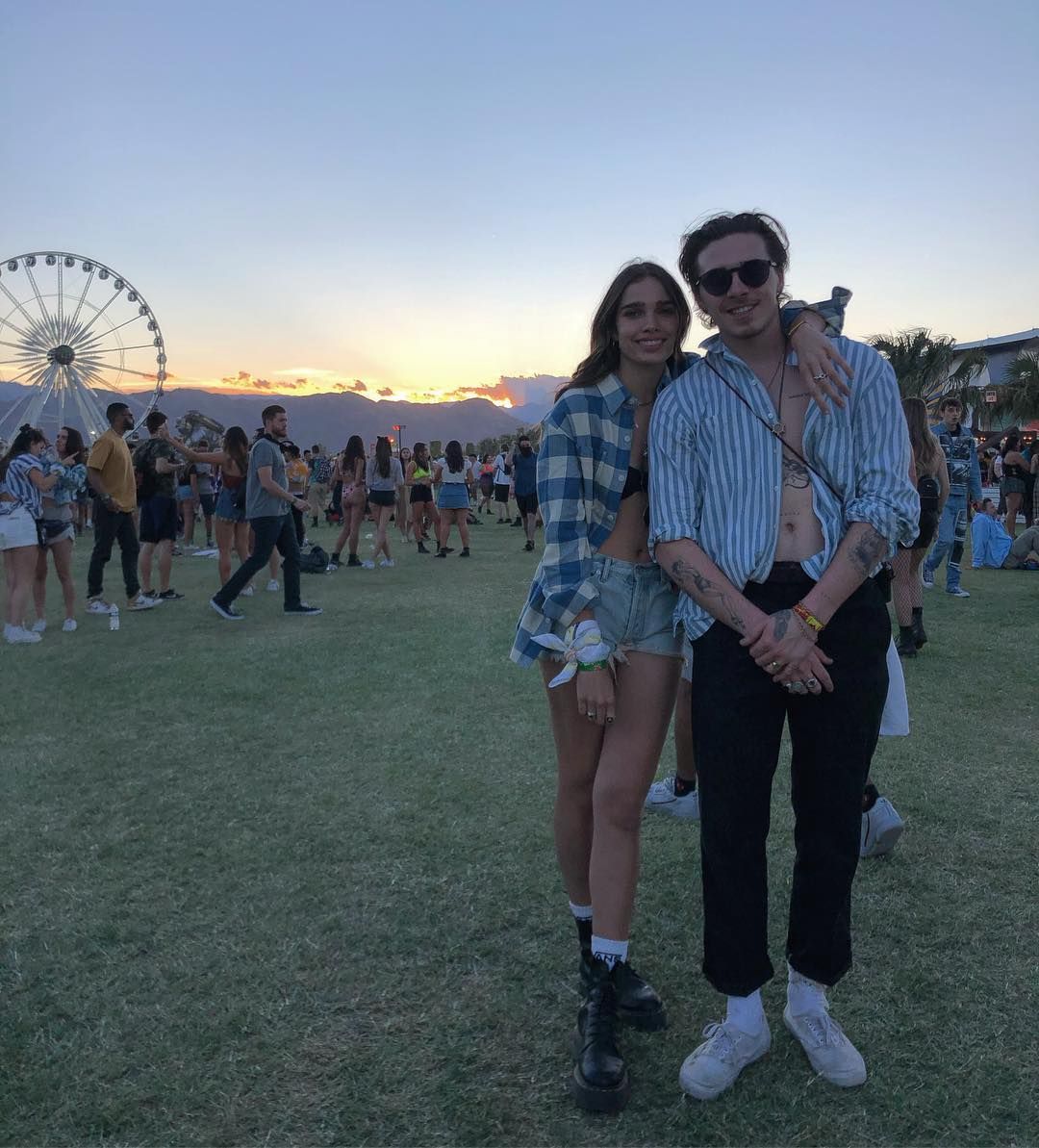 Image may contain: Brooklyn Beckham and Hana Cross, Brooklyn Beckham, Hana Cross, relationship, together, split, breakup, reason, argument, timeline, dating, drama, Instagram, People, Grass, Plant, Crowd, Amusement Park, Ferris Wheel, Shoe, Footwear, Accessory, Sunglasses, Accessories, Clothing, Apparel, Shorts, Human, Person