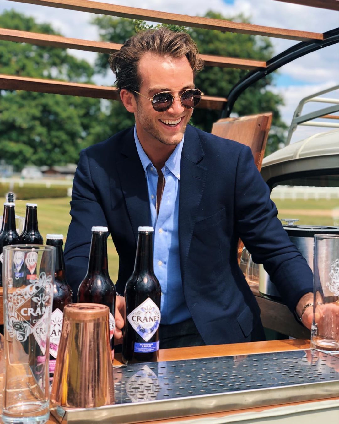 Image may contain: Stout, Wine, Beer Bottle, Coat, Suit, Clothing, Apparel, Overcoat, Bottle, Accessory, Accessories, Sunglasses, Drink, Beverage, Beer, Alcohol, Human, Person