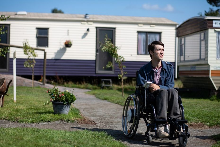 Image may contain: Urban, Neighborhood, Wheel, Machine, Mobile Home, Human, Person, Building, Housing, Chair, Furniture, sex education season two new cast, george robinson, isaac, netflix