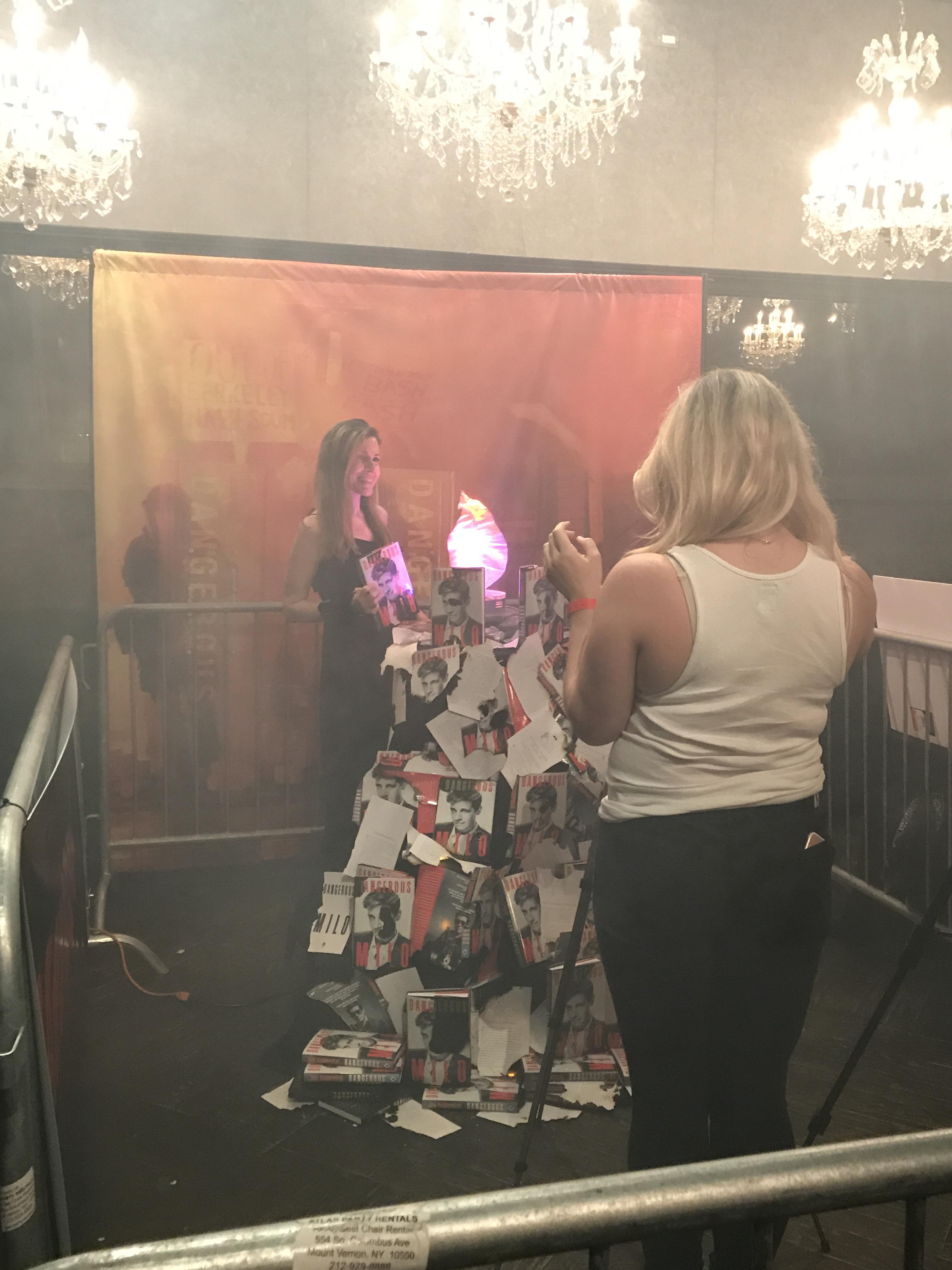 Woman taking pictures with Milo's burning books