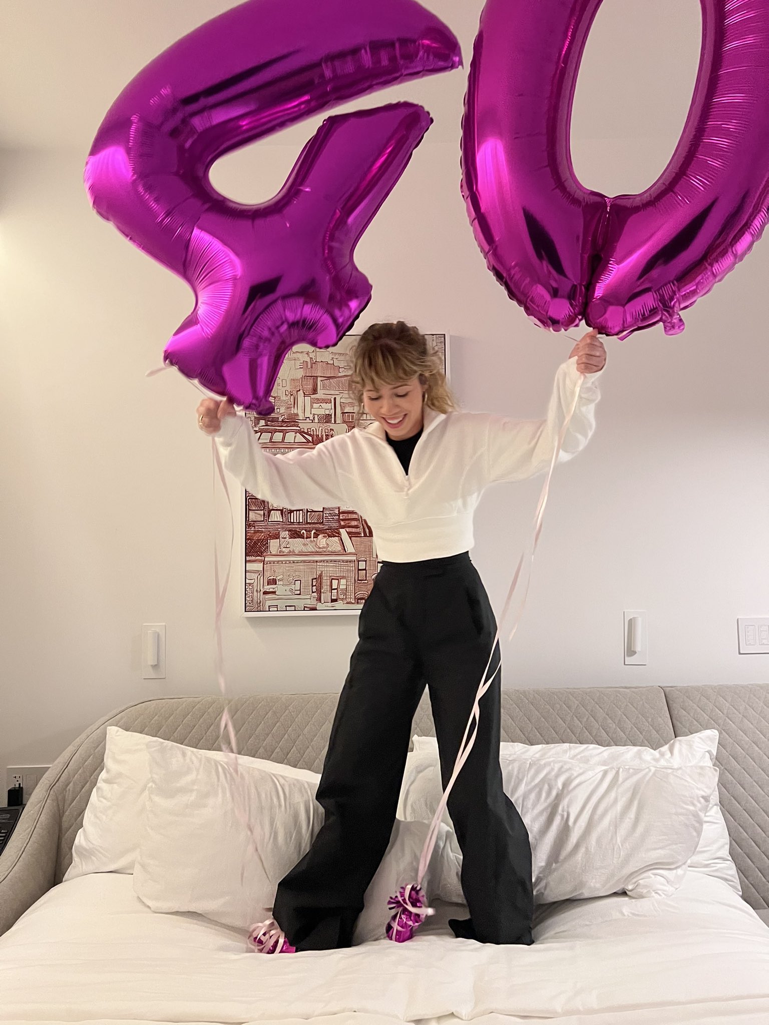 Jennette McCurdy standing on a bed with purple 40 balloons