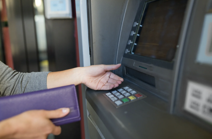 A woman taking money out of a cash machine, where students have reported instances of 'aggressive begging' in Durham 