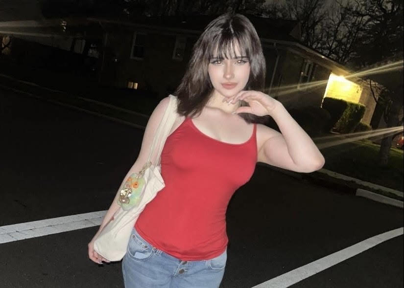 Maria posing in a red top and jeans