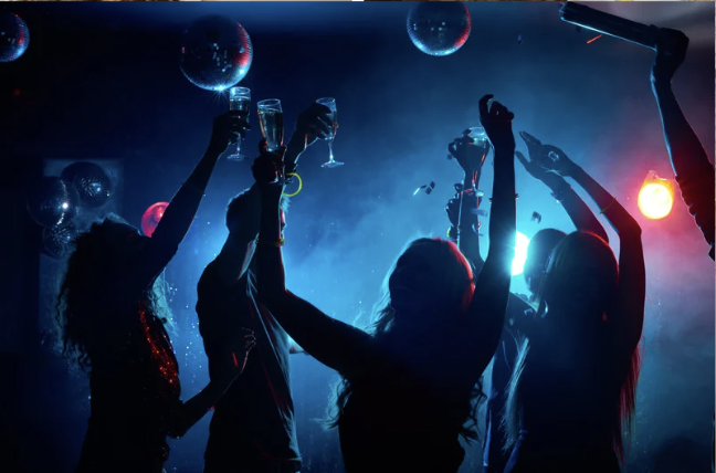 People dancing in a dimly lit club, where a spiking incident may occur