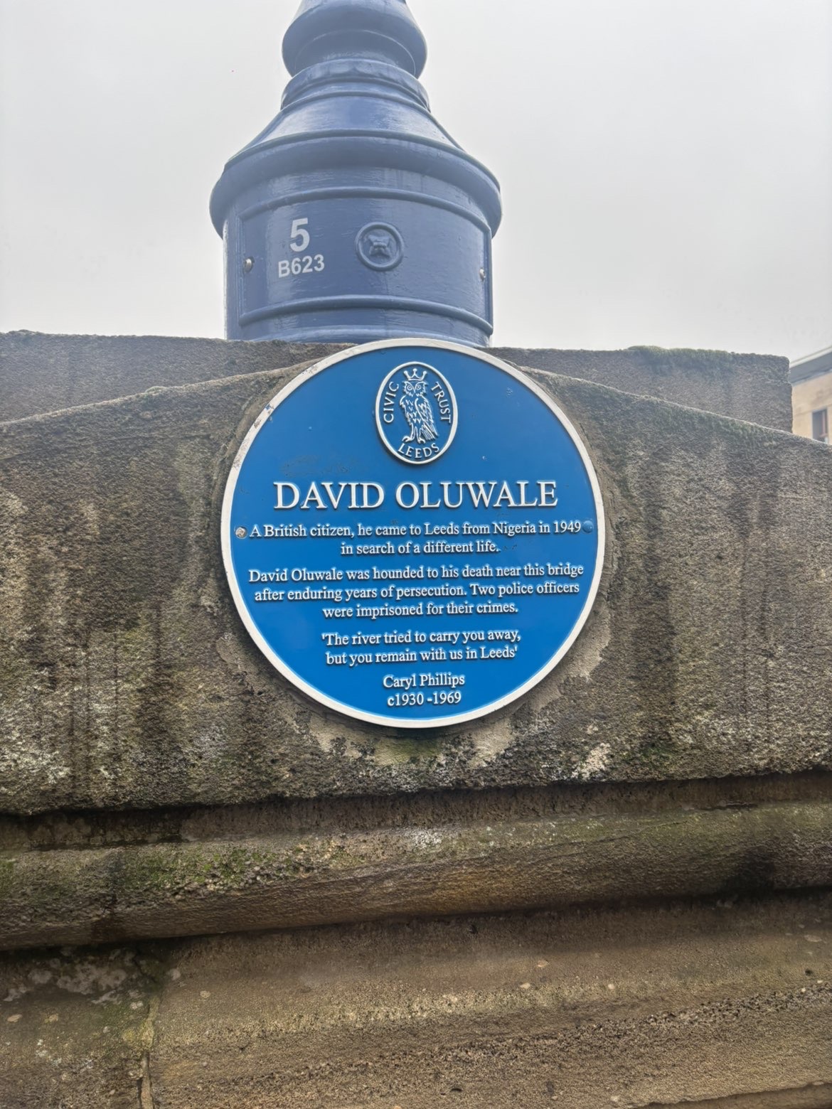 The image shows a blue plaque on a stone wall